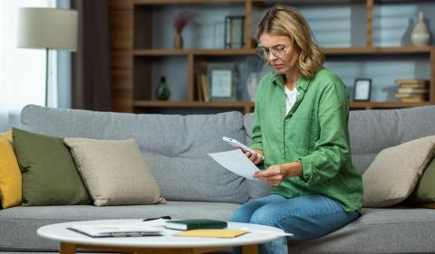 Person sitting on couch holding a smartphone and paper image